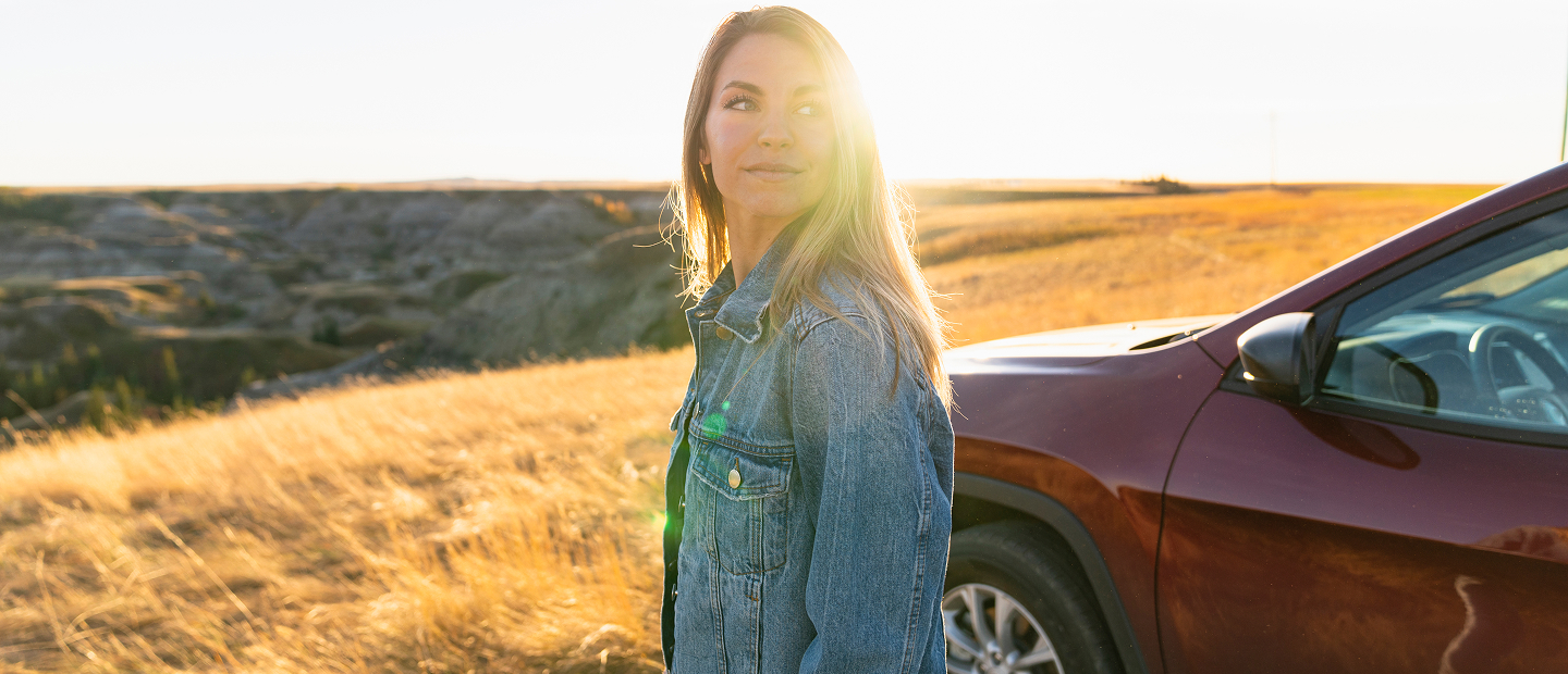 Woman in denim at sunset by car