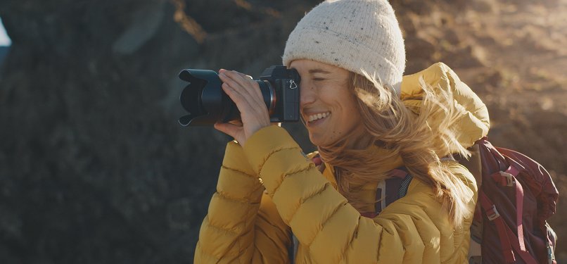 Photographer with camera in yellow jacket on a coastal mountain